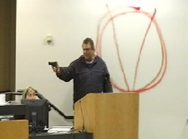 In this image taken from video and released by WJHG-TV, Clay A. Duke points a hand gun at Bay City school board members and staff on Tuesday.